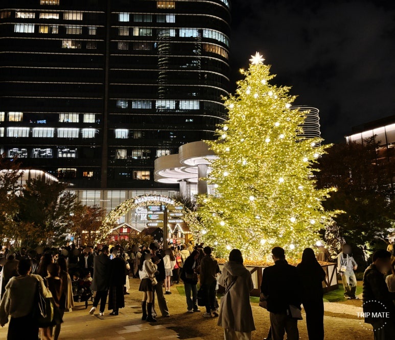 Families taking photos under the champagne gold Christmas tree at Azabudai Hills Christmas Market